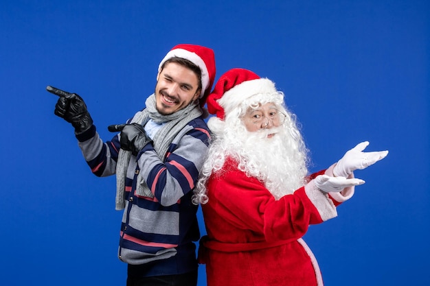 Free photo front view of santa claus with young man on blue wall