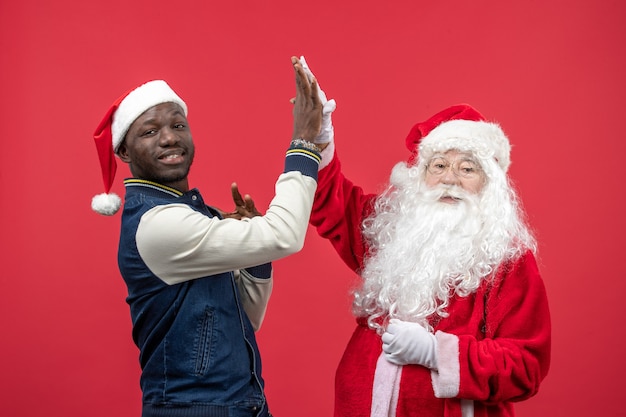 Front view of santa claus with young man on red wall