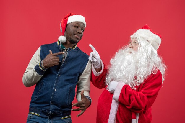 Front view of santa claus with young man on red wall