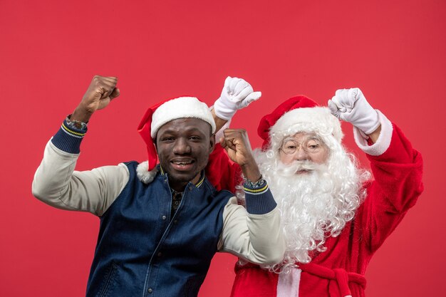 Front view of santa claus with young man on the red wall