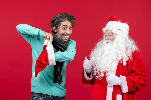 Front view of santa claus with young man standing on red wall