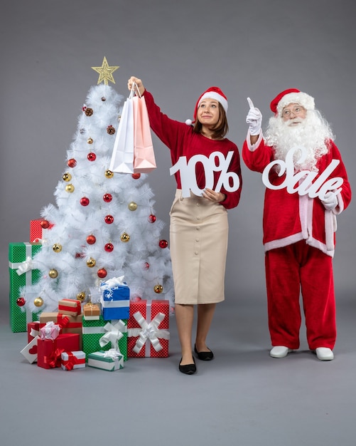 Front view santa claus with young woman holding and sale writings on a grey background