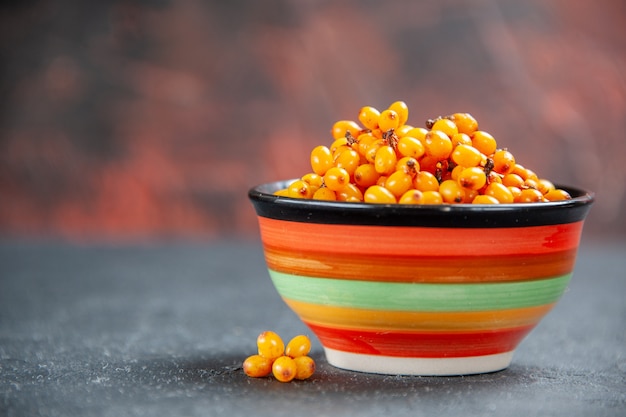 Front view sea buckthorn in bowl on dark red surface copy place