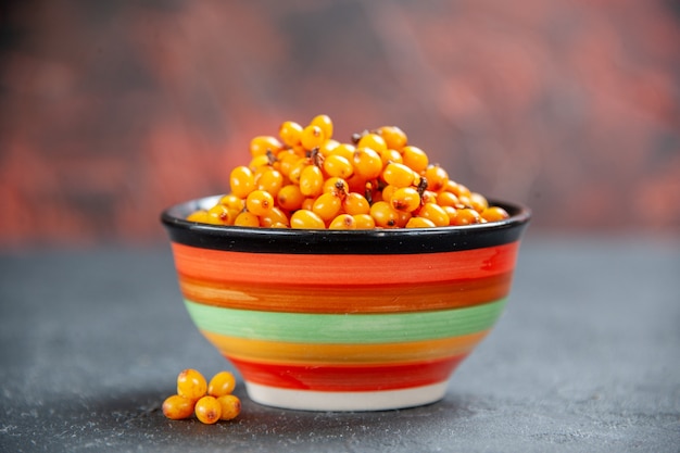 Free Photo front view sea buckthorn in bowl on dark red surface copy place