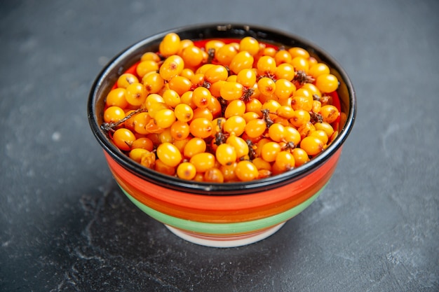 Front view sea buckthorn in bowl on dark red surface