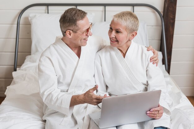 Front view senior couple looking on a laptop in bed together