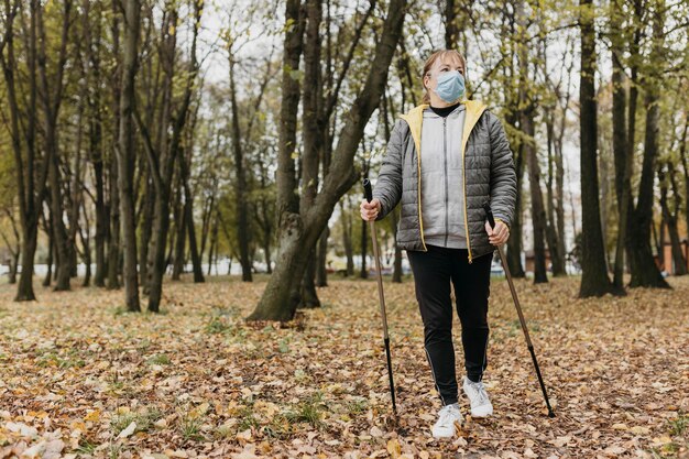 Front view of senior woman with medical mask and trekking sticks