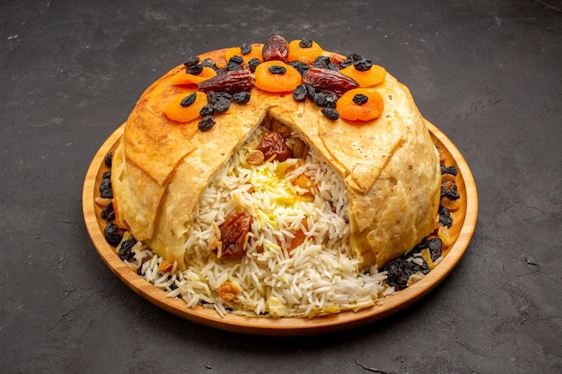 Free photo front view shakh plov delicious rice meal cooked inside round dough with raisins on grey space