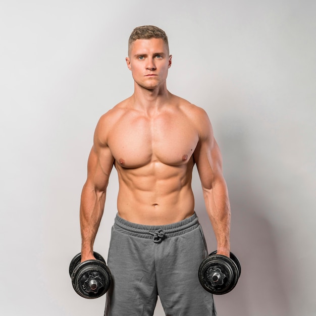 Free photo front view of shirtless fit man posing while holding weights