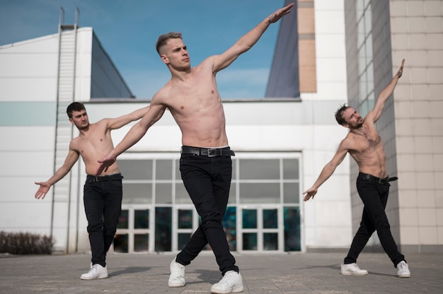 Free photo front view of shirtless hip hop dancers rehearsing outside