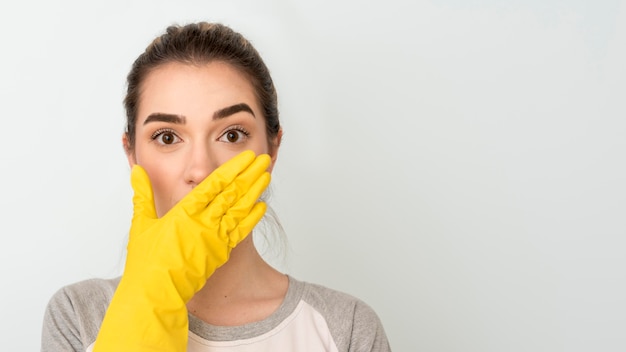 Front view of shocked woman with cleaning glove on hand