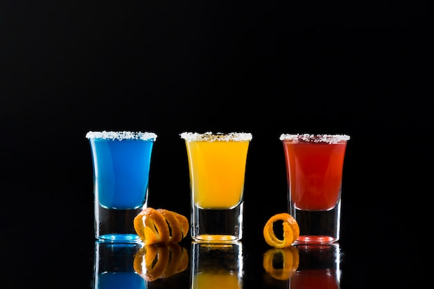 Front view of shot glasses with colorful cocktails