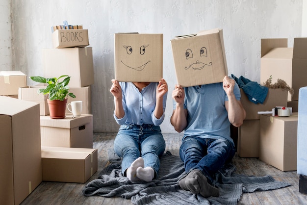 Free photo front view of silly couple with boxes over heads at home on moving day