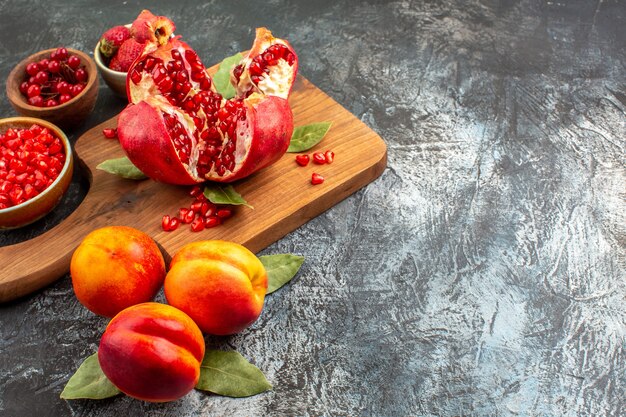 Front view sliced pomegranates with peaches on dark table garden tree fruit