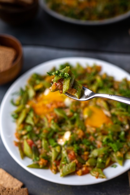 A front view sliced vegetable meal colorful tasty inside white plate along with crisps eggs on the grey table dish vegetables