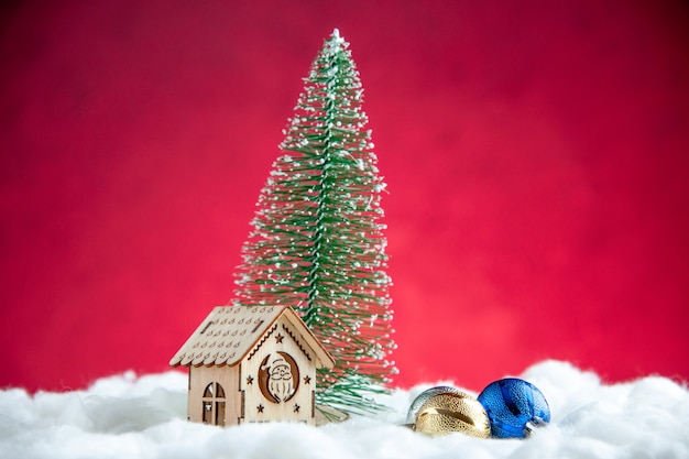 Free Photo front view small xmas tree small wood house on red surface