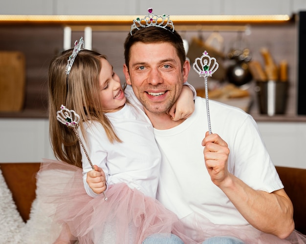 Front view of smiley father and daughter playing with tiara and wand