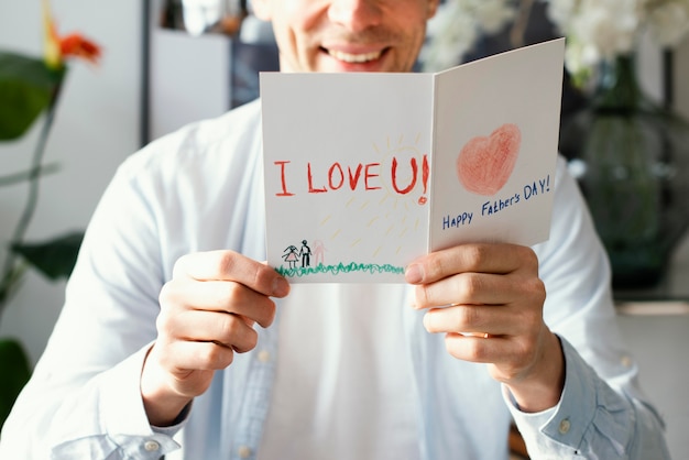 Free photo front view of smiley father reading his father's day card