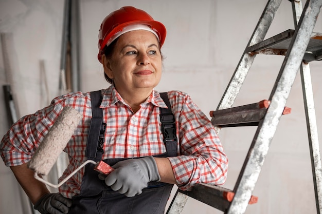 Free photo front view of smiley female construction worker with paint roller