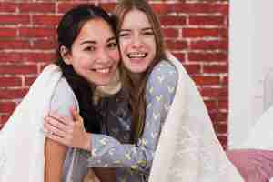 Free photo front view smiley females sharing blanket