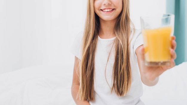 Front view smiley girl holding a glass of orange juice