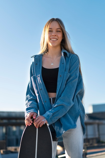 Free Photo front view smiley girl holding skateboard