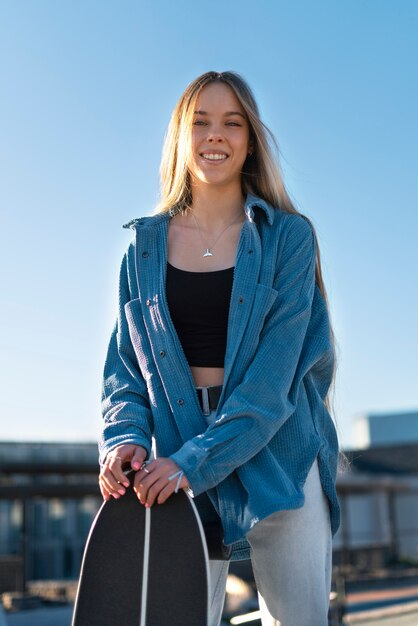 Front view smiley girl holding skateboard