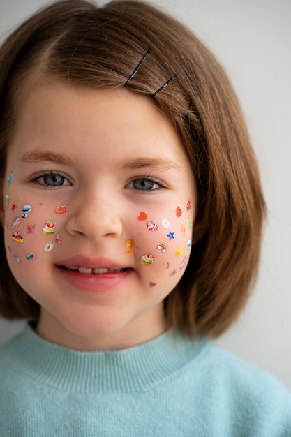 Free photo front view smiley girl with stickers on face