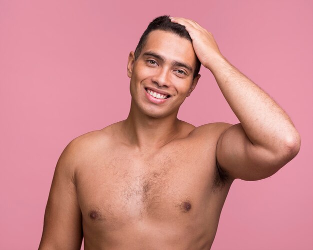 Front view of smiley handsome man posing shirtless