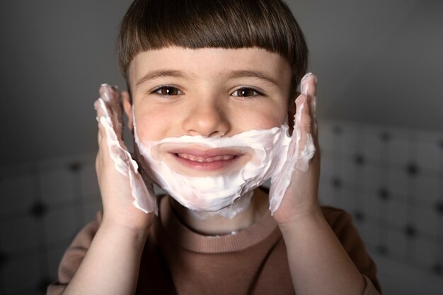 Front view smiley kid using shaving cream