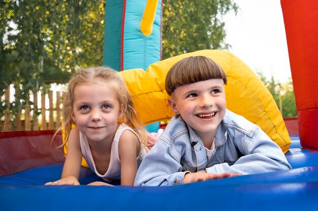 Front view smiley kids laying in bounce house