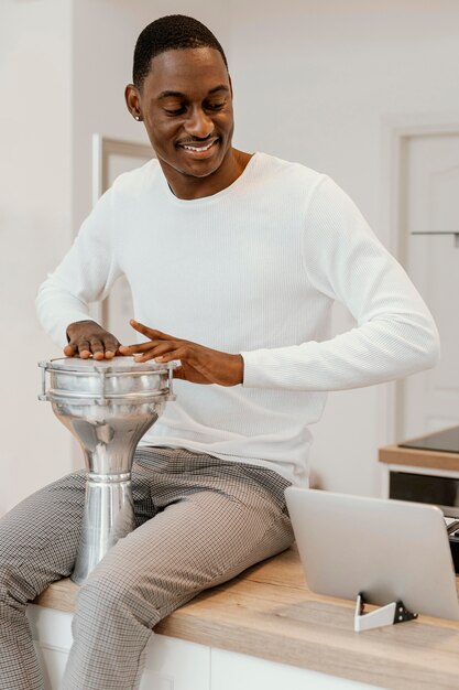 Front view of smiley male musician at home playing drums