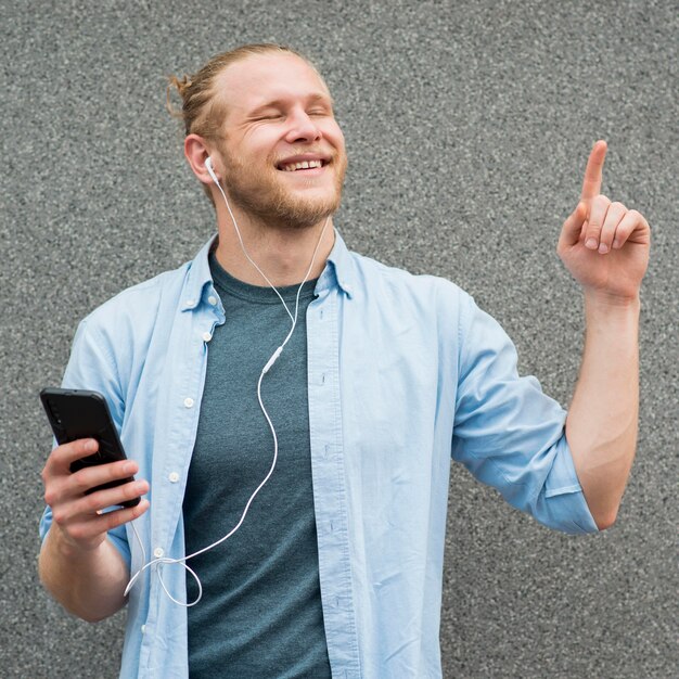 Front view of smiley man listening to music on earphones