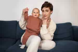 Free photo front view smiley mother on couch with baby