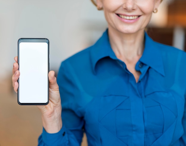 Front view of smiley older business woman holding smartphone