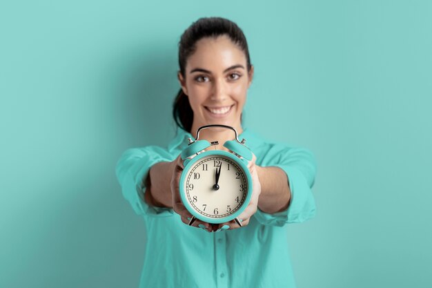 Front view of smiley woman holding clock