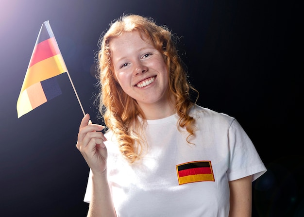 Free photo front view of smiley woman holding german flag