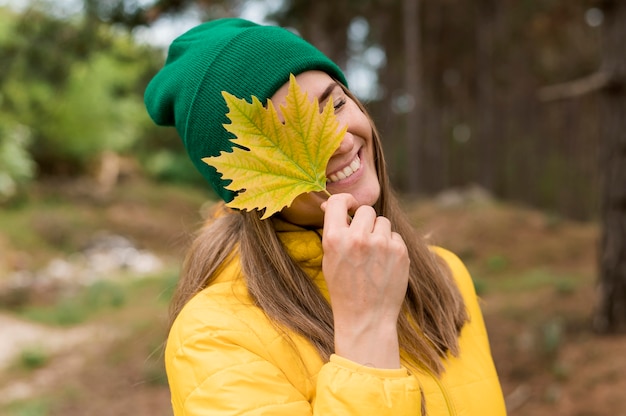 Front view smiley woman holding a yellow leaf