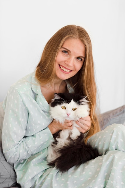 Free Photo front view of smiley woman in pajamas holding cat