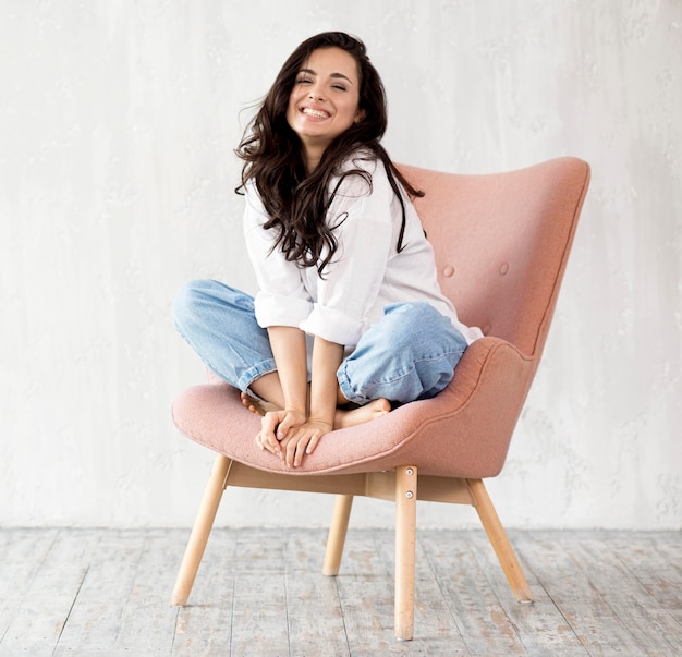 Front view of smiley woman posing on chair