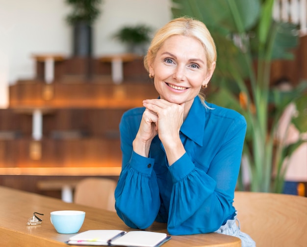 Free Photo front view of smiley woman posing while having coffee and working