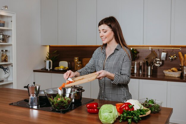 Front view of smiley woman preparing food in the kitchen at home