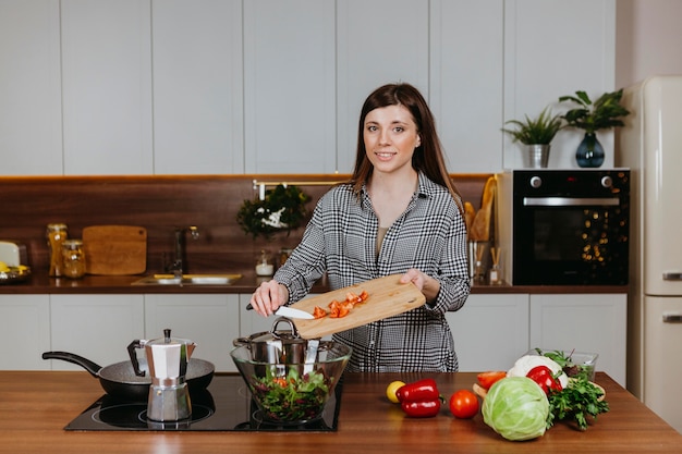 Front view of smiley woman preparing food in the kitchen