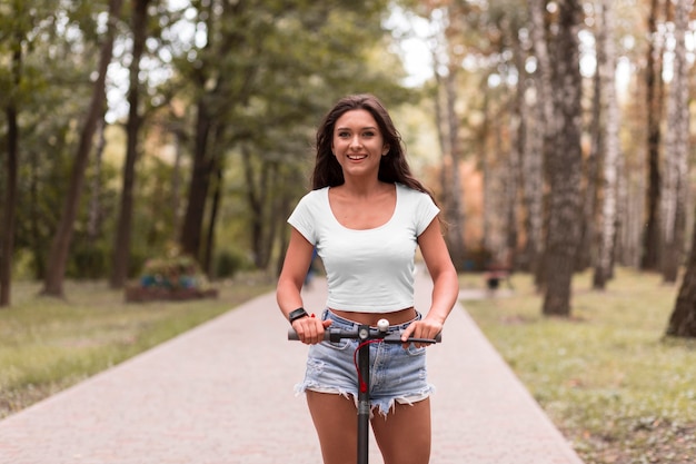 Free photo front view of smiley woman riding an electric scooter