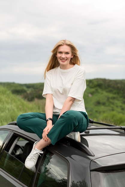 Free photo front view of smiley woman standing on car