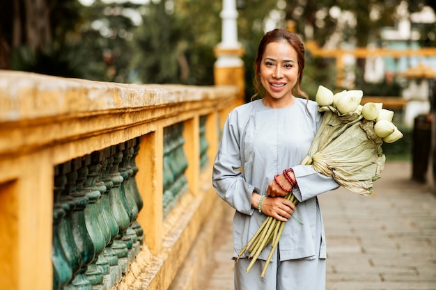 Front view of smiley woman at the temple with bouquet of flowers