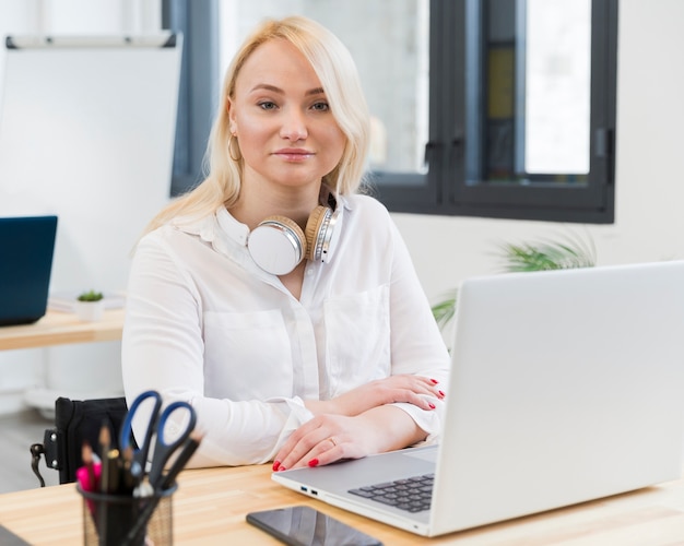 Front view of smiley woman in wheelchair posing at her desk