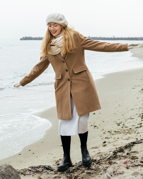 Free Photo front view of smiley woman with mittens at the beach during winter