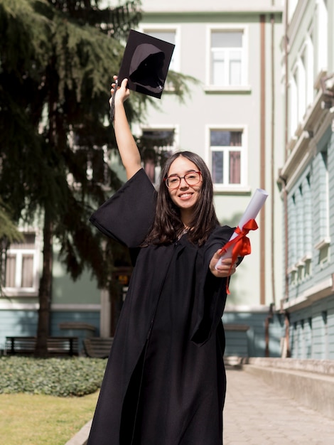 Front view smiley young woman wearing graduation gown