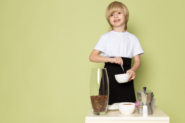 Free photo a front view smiling cute boys in white t-shirts preparing coffee drink on the stone colored space